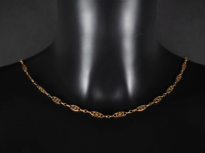 Collier ras de cou en plaqué or, maillons ajourés, à décor filigrané. 