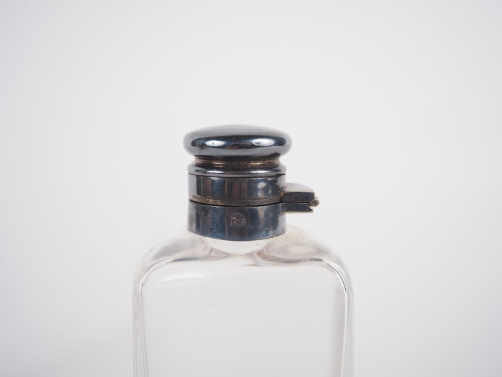 Sacoche en cuir brun contenant une boîte en métal argenté et un flacon