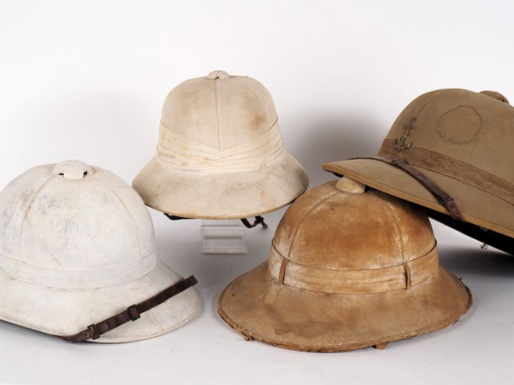Quatre casques coloniaux.  En liège, deux recouvert de toile blanchie 
